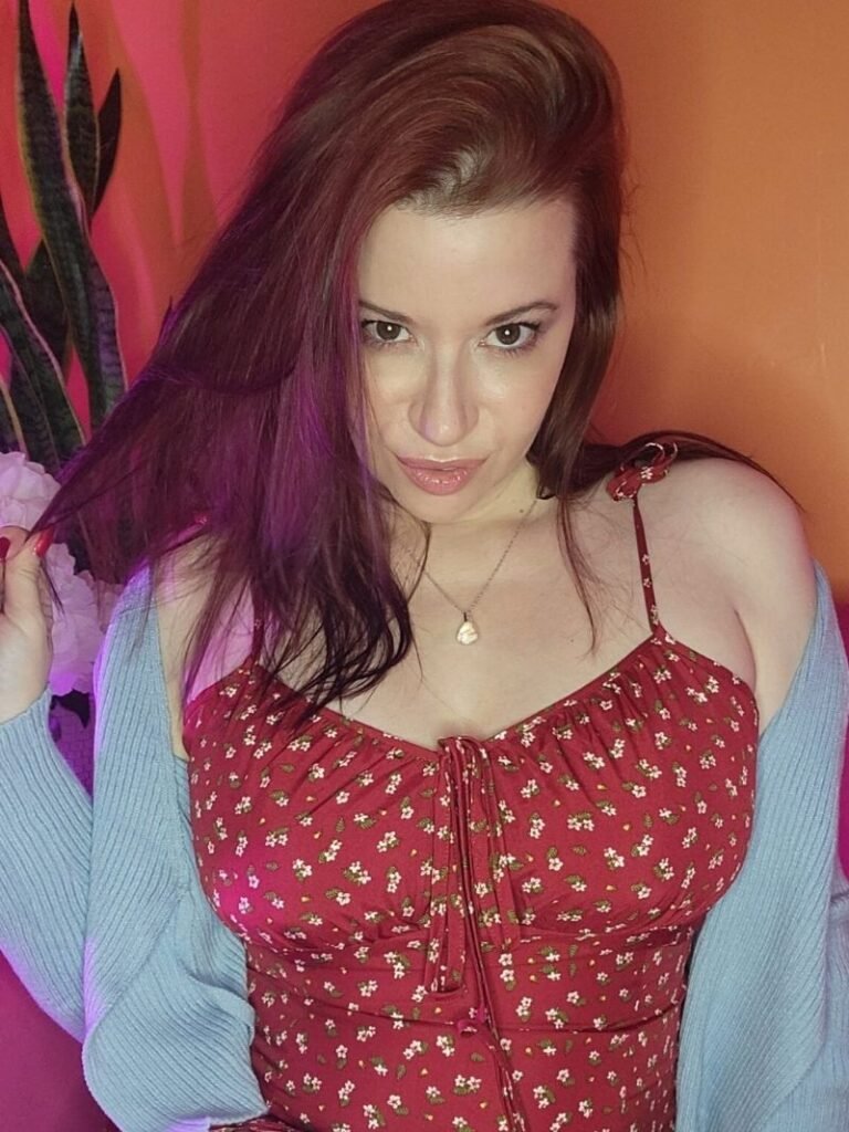 Sarah Blake in a red floral sundress, sweet smile with a teasing streak